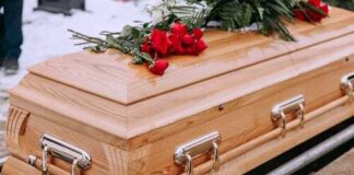 A wooden coffin adorned with red roses at a burial site