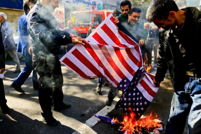 Group burning American flag on street pavement
