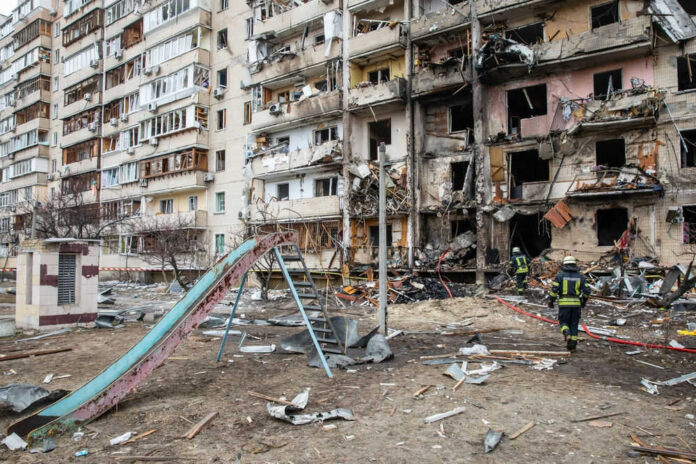 Firefighters inspect debris in front of damaged building
