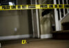 Yellow police tape inside home near staircase evidence marker