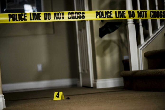 Yellow police tape inside home near staircase evidence marker