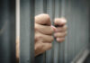 Hands gripping prison bars tightly