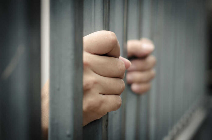 Hands gripping prison bars tightly