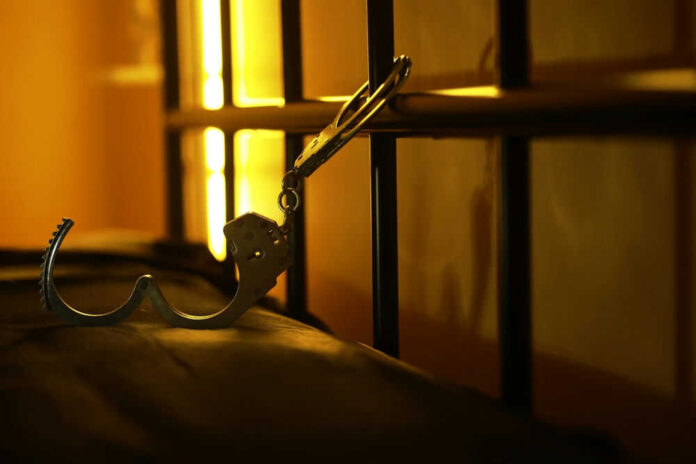 Open handcuffs hanging in dimly lit cell