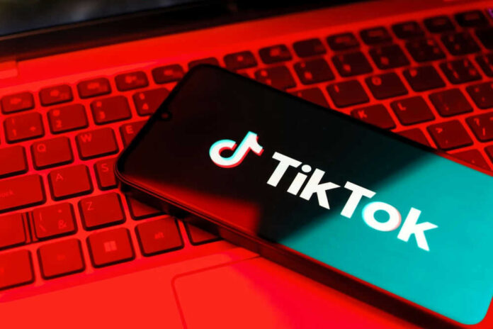 Smartphone with TikTok logo on red laptop keyboard