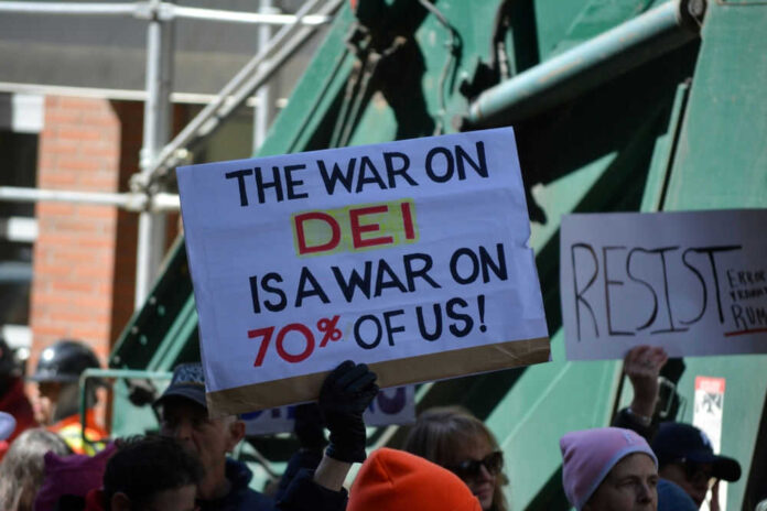 Protesters holding signs including The War on DEI