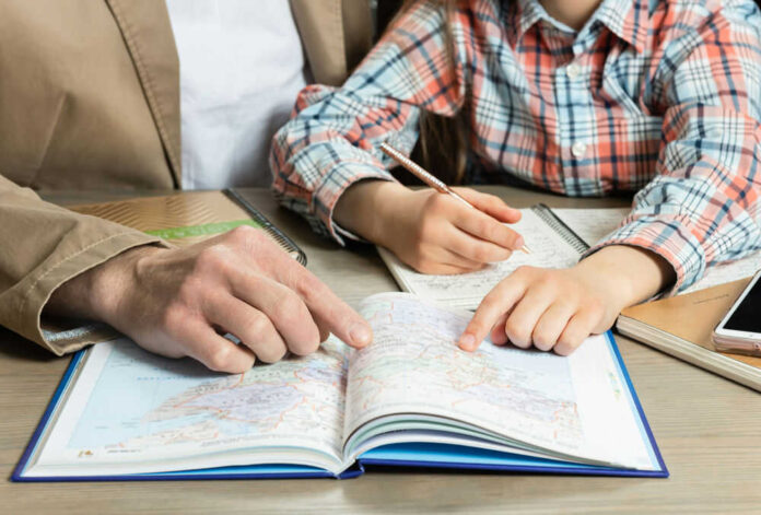 Two people studying map with notebooks and phone