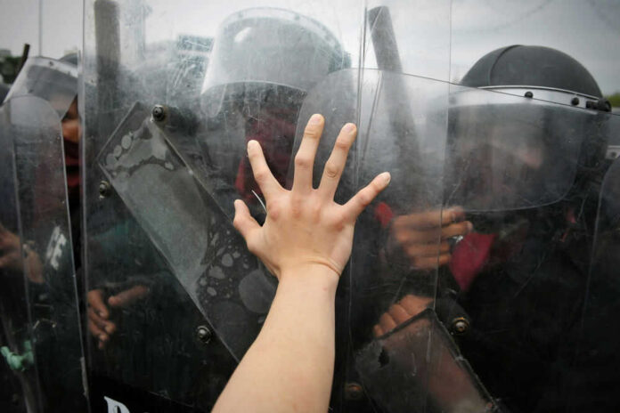 Hand reaching out to police riot shields