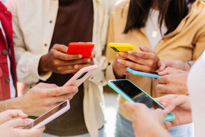 Group of people holding colorful smartphones outdoors