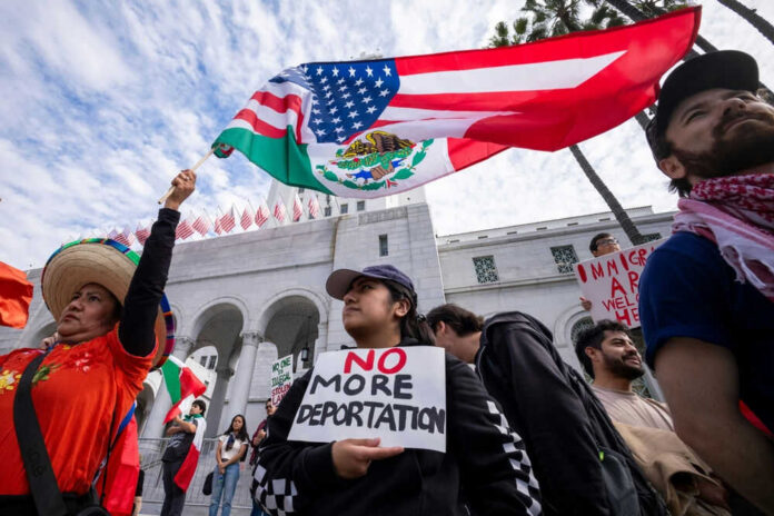 Protesters holding antideportation signs and mixed flags