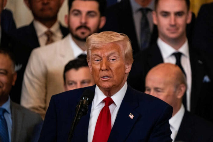 Man speaking at podium surrounded by people in suits