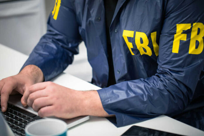 Person in FBI jacket using a laptop