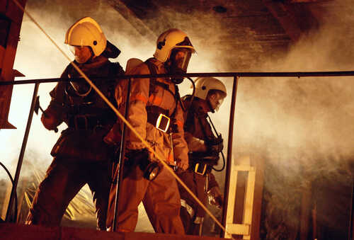 Firefighters in protective gear navigating through smoke