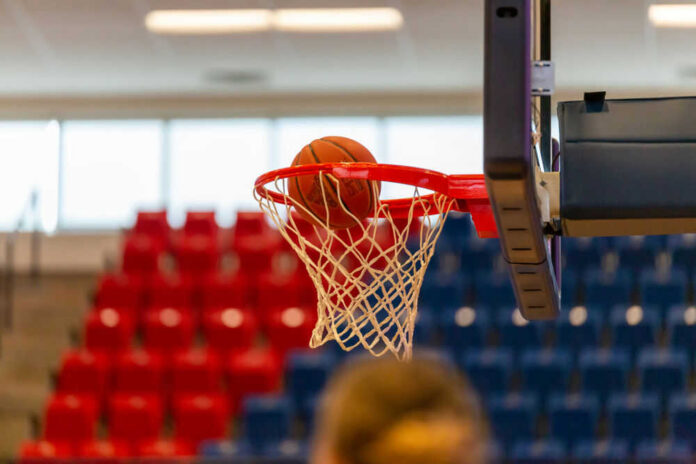 Basketball going through hoop in gymnasium setting
