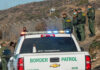 Border Patrol agents gathered near a fence outdoors
