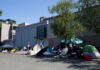 Tents and belongings on a street beside buildings