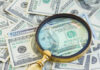 Magnifying glass over US hundred dollar bills