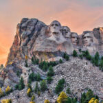 Mount Rushmore with trees and colorful sky background