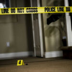 Yellow police tape inside home near staircase evidence marker