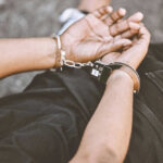 Person handcuffed lying on the ground outdoors