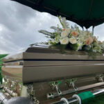 Casket with floral arrangement under cloudy sky