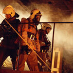 Firefighters in protective gear navigating through smoke