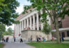 People walking outside a building with columns and trees