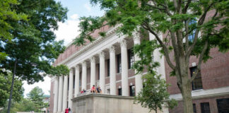 People walking outside a building with columns and trees