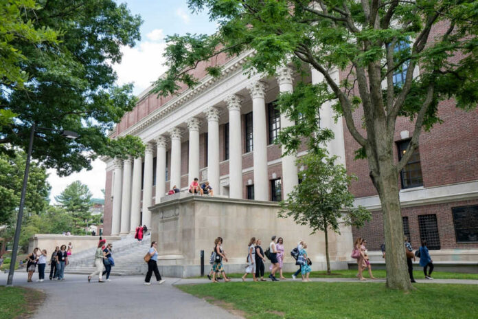 2314386007 People walking outside a building with columns and trees