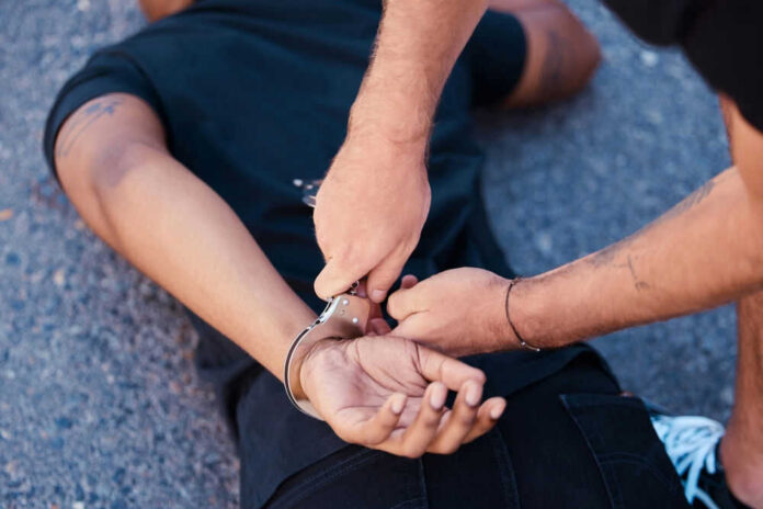 2214250637 Person being handcuffed on the ground outdoors