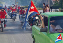 People riding motorcycles and car with Cuban flags