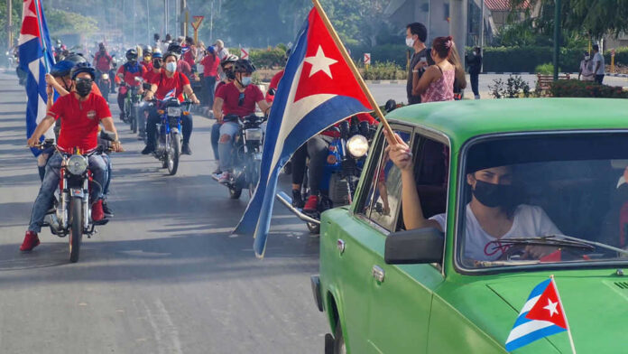 People riding motorcycles and car with Cuban flags
